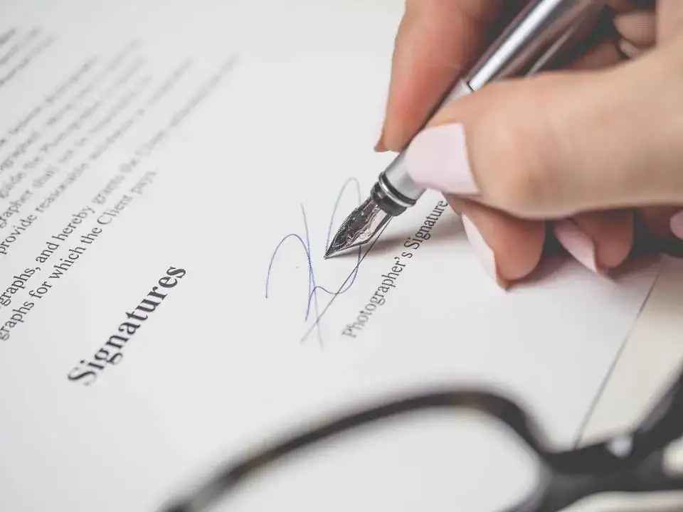 Persona firmando un documento con pluma estilográfica, como la escritura de un divorcio en notaría